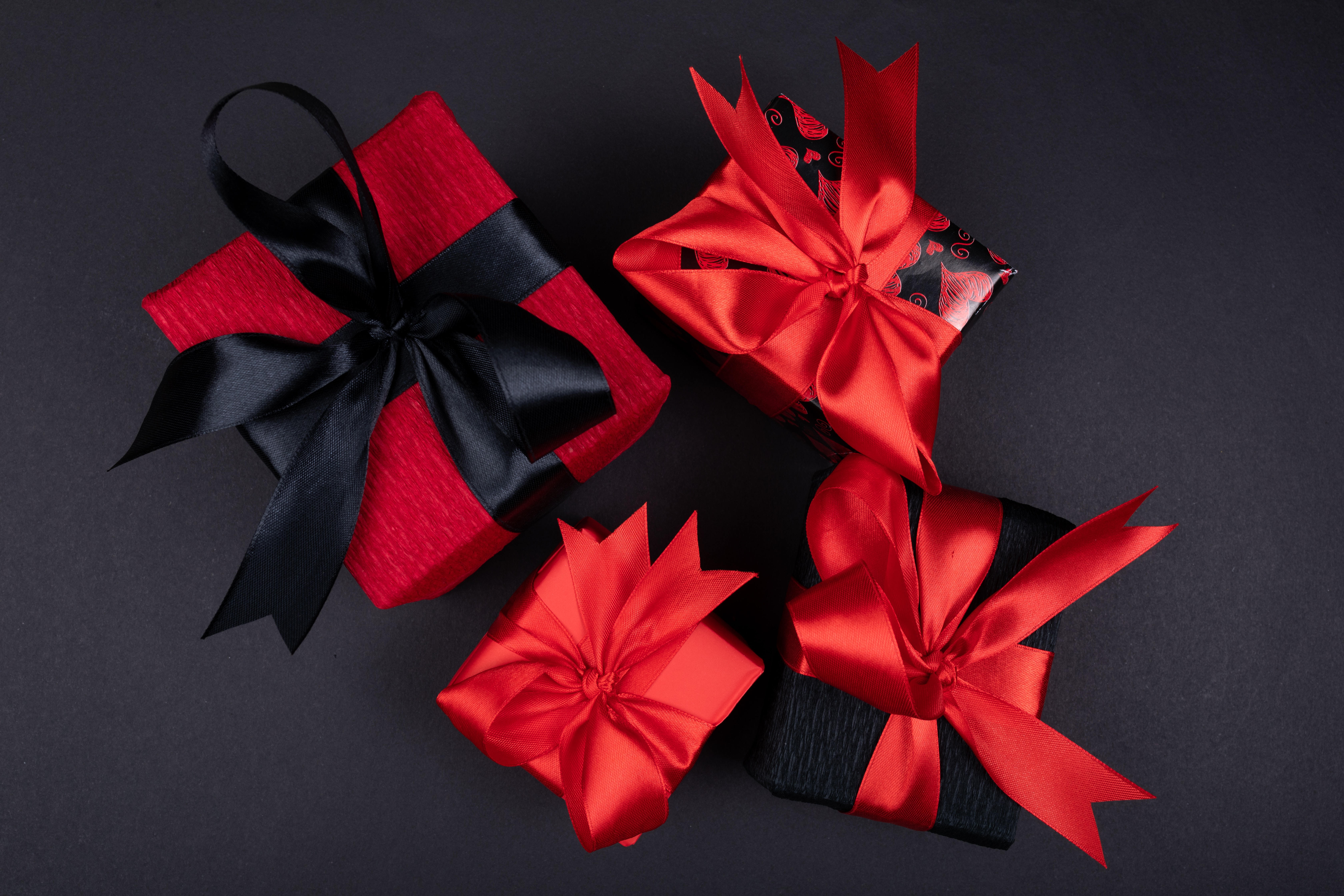 Overhead view of several wrapped gifts with red ribbons.