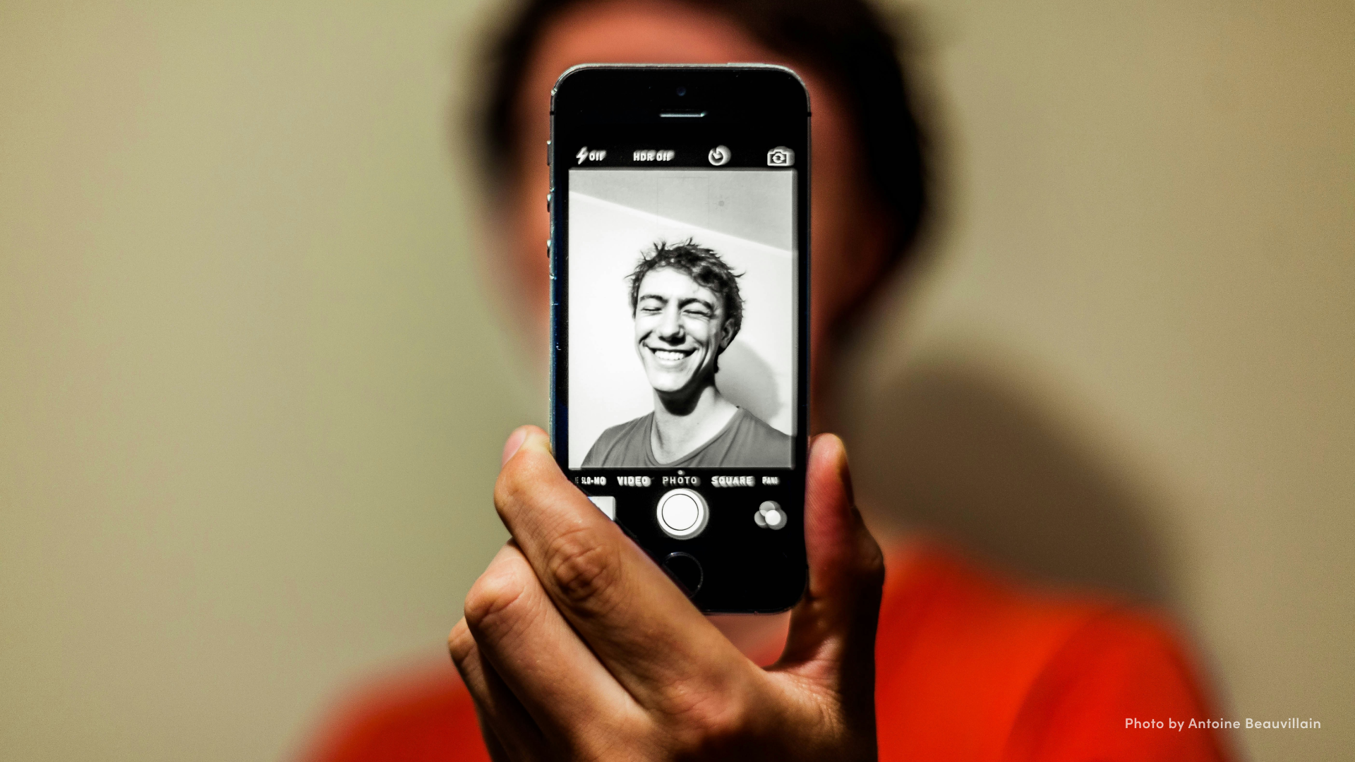 Man holding a phone in front of his face, taking a selfie.